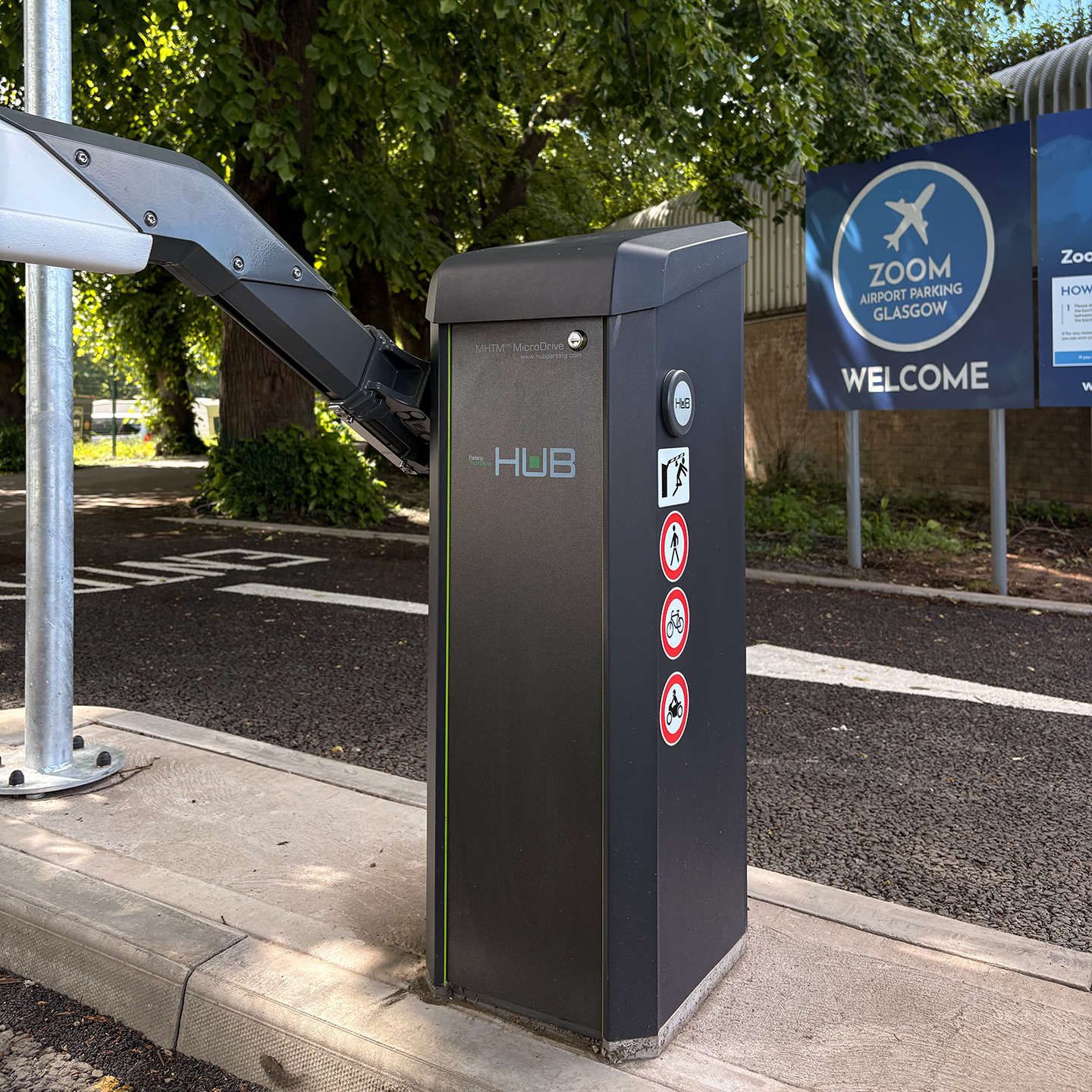 Close-up of the automated HUB entry barrier system and blue Zoom Airport Parking Glasgow welcome sign at the car park entrance.